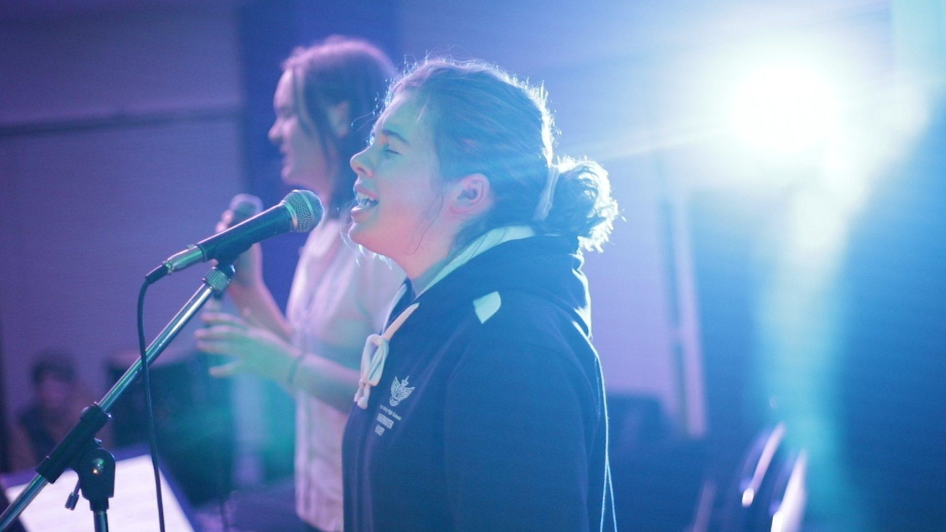 A student singing confidently on stage